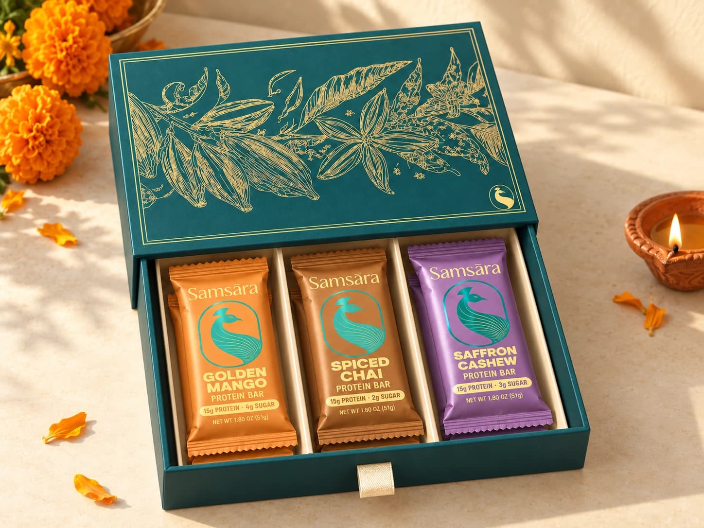 Festive drawer gift box with Mango, Chai, and Saffron Cashew bars beside marigolds and a diya
